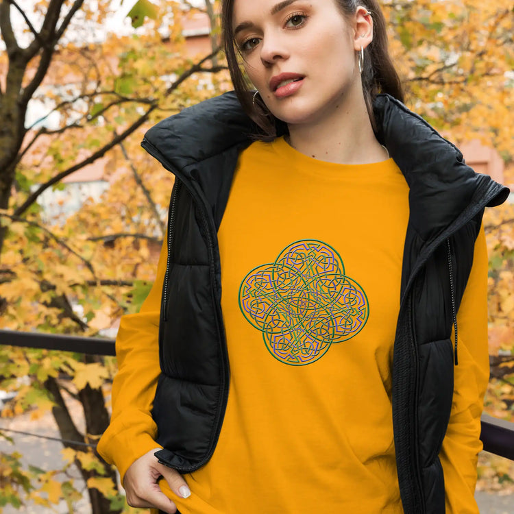 A young woman wearing a gold Xigfireon long sleeve graphic t-shirt featuring the Living Colour iteration of the Reach Of The Spirit Celtic knot design. The Reach Of The Spirit Celtic knot symbolizes Mother Earth.