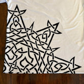 A closer look at the bottom right print on the front of a white Xigfireon graphic mens t-shirt featuring the Black Sunset iteration of the Morning Star Fire Celtic knot design.