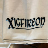 A close-up of the sleeve logo on a white Xigfireon graphic mens t-shirt featuring the Black Sunset iteration of the Morning Star Fire Celtic knot design.