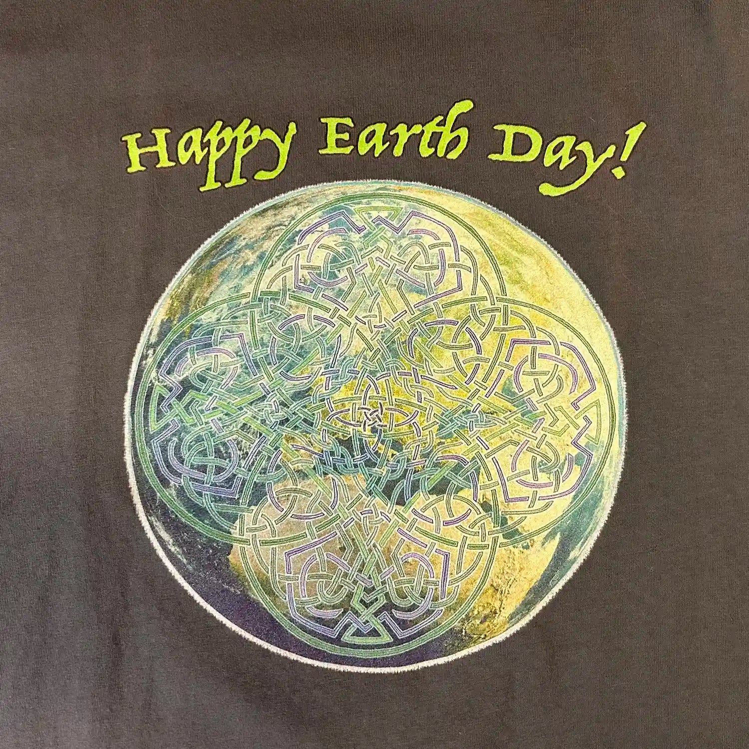 A close-up of a stargazer organic graphic t-shirt featuring the Sacred Planet iteration of the Reach Of The Spirit Celtic knot design under a message reading "Happy Earth Day".