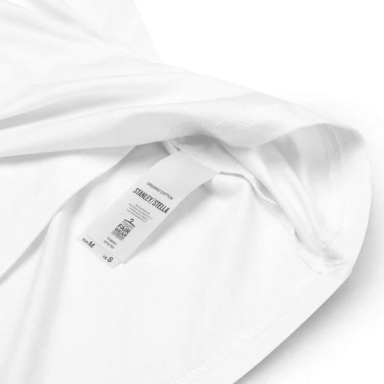 A close-up view of a product tag on a white Xigfireon graphic organic cotton t-shirt featuring the Living Colour iteration of the Reach Of The Spirit Celtic knot design. The Reach Of The Spirit Celtic knot represents our amazing Mother Earth.