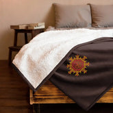 A bed made up with a fireside brown Xigfireon sherpa blanket embroidered with the Fire Colour iteration of the Morning Star Fire Celtic knot design.