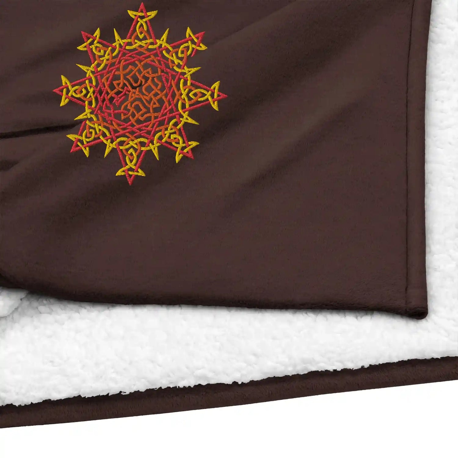 A close-up view of a fireside brown Xigfireon sherpa blanket embroidered with the Fire Colour iteration of the Morning Star Fire Celtic knot design.