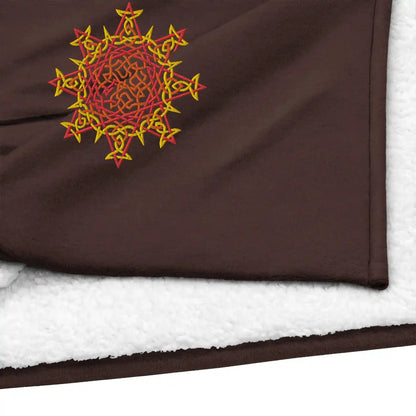 A close-up view of a fireside brown Xigfireon sherpa blanket embroidered with the Fire Colour iteration of the Morning Star Fire Celtic knot design.