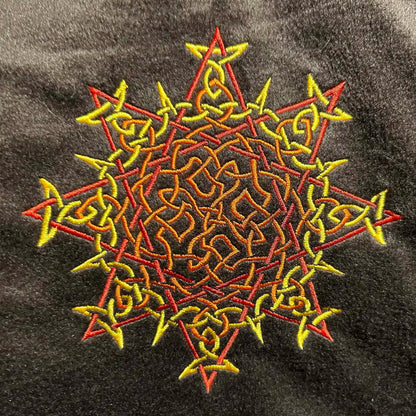 A close-up of a fireside brown Xigfireon sherpa blanket embroidered with the Fire Colour iteration of the Morning Star Fire Celtic knot design. The Morning Star Fire Celtic knot represents Father Sun.