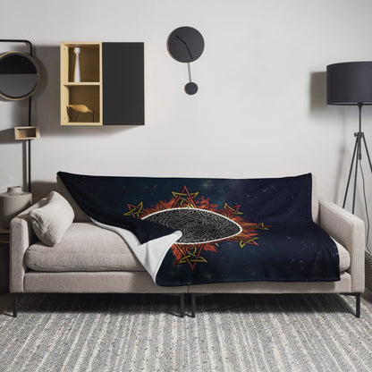 A sofa covered by a 60 inch by 80 inch Xigfireon throw blanket featuring the Eclipsed iteration of the Morning Star Fire Celtic knot design. Inspired by the 2023 Annular Solar Eclipse.