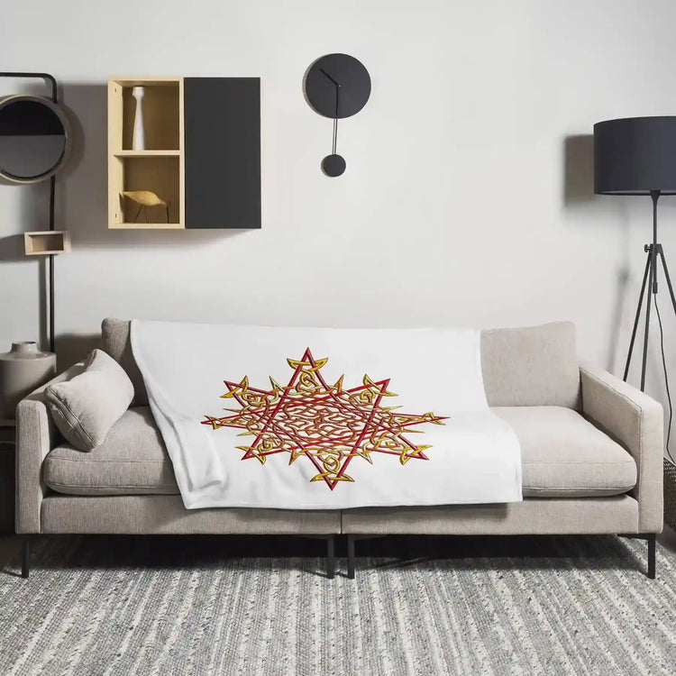A sofa covered by a 50 inch by 60 inch Xigfireon throw blanket featuring the Fire Colour iteration of the Morning Star Fire Celtic knot design. The Morning Star Fire Celtic knot represents the Sun.