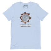 A light blue short-sleeve t-shirt by Xigfireon with a central graphic of a solar eclipse. The graphic features a detailed Celtic knot Sun surrounded by rays with the Spanish text &