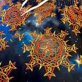 A close look at the printed fabric on a pair of Xigfireon graphic swim trunks featuring the Fire Colour Cosmos (Small) patterned series of the Morning Star Fire Celtic knot design.