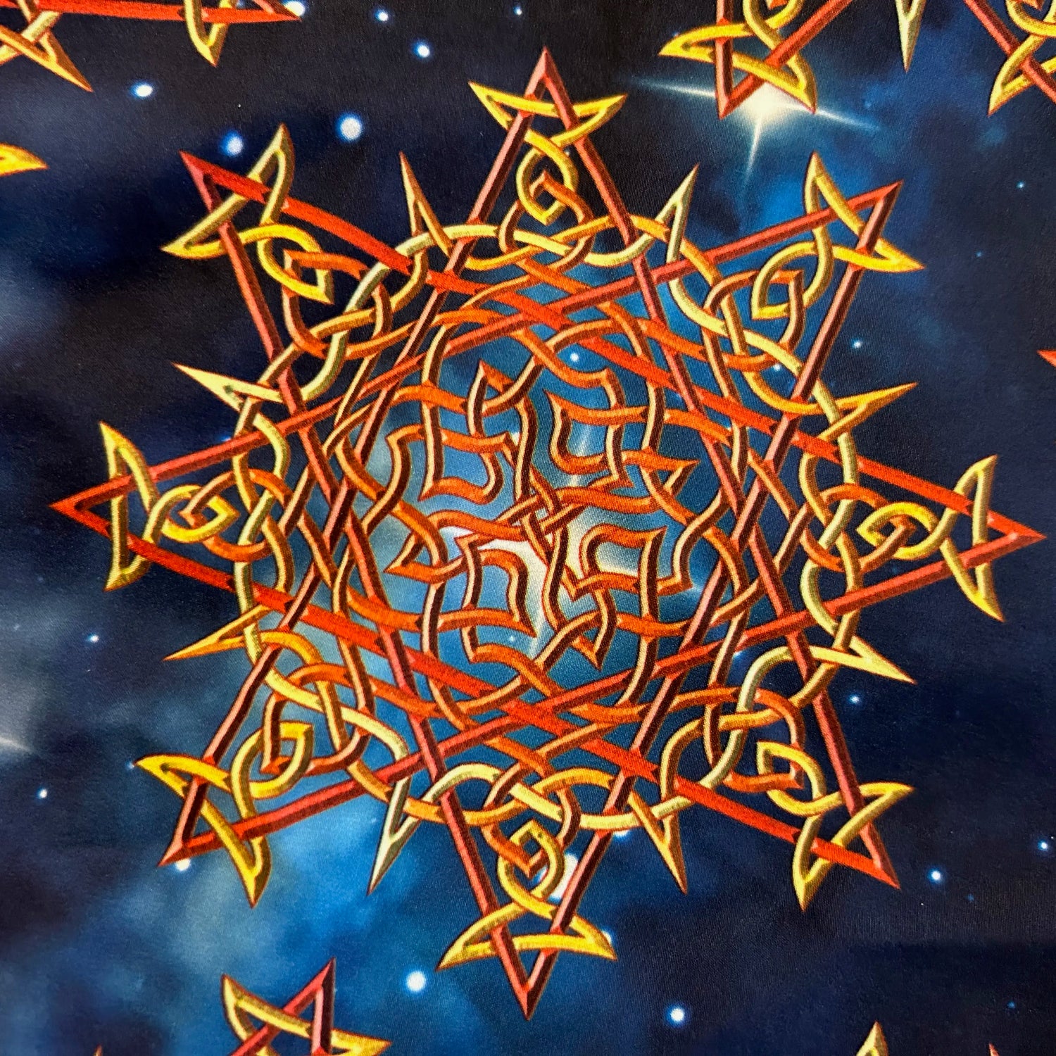 A even closer look at the printed fabric on a pair of Xigfireon graphic swim trunks featuring the Fire Colour Cosmos (Small) patterned series of the Morning Star Fire Celtic knot design.
