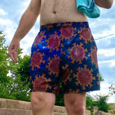A man, viewed from the front, wearing a pair of Xigfireon graphic swim trunks featuring the Fire Colour Cosmos (small) patterned series of the Morning Star Fire Celtic knot design.