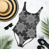 A sunhat, sun glasses, and beach sandals displayed with a Xigfireon graphic swimsuit featuring the Black & White Solid Cosmos patterned series of the Morning Star Fire Celtic knot design.