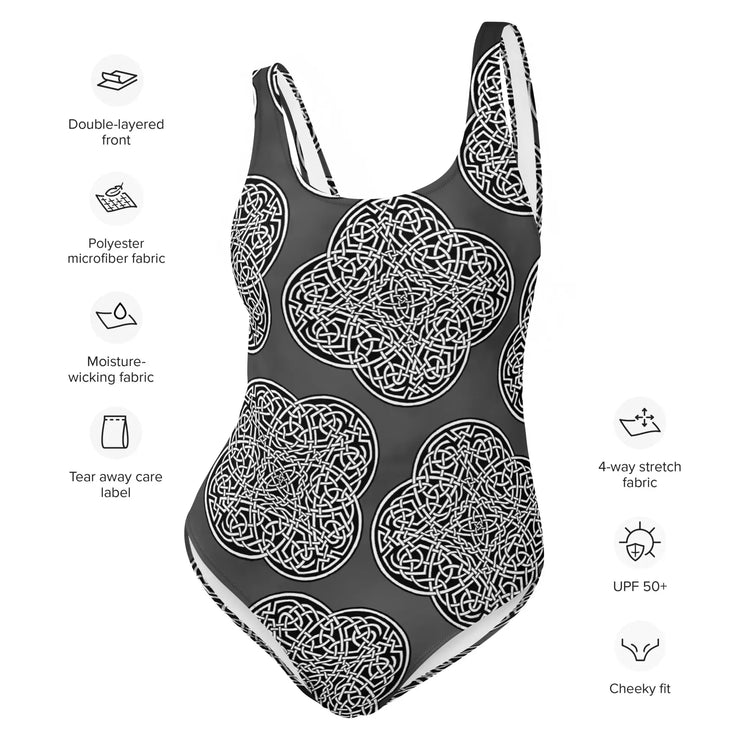 A list of product features surrounding a Xigfireon graphic swimsuit featuring the Black & White Solid Forest patterned series of the Reach Of The Spirit Celtic knot design. Features include double-layered front, polyester microfiber fabric, moisture-wicking fabric, tear away care label, 4-way stretch, UPF 50+, and cheeky fit.
