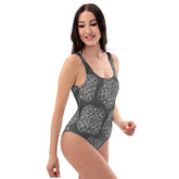 A woman, viewed from the front, wearing a Xigfireon graphic swimsuit featuring the Black & White Solid Forest patterned series of the Reach Of The Spirit Celtic knot design.