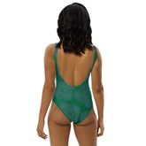 A woman, viewed from behind, wearing a Xigfireon graphic swimsuit featuring the Living Colour Forest patterned series of the Reach Of The Spirit Celtic knot design.