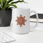 An office desktop displaying a Xigfireon white ceramic 15oz mug featuring the Fire Colour iteration of the Morning Star Fire Celtic knot design. This Celtic knot symbolizes Father Sun.