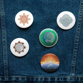 A jean jacket with 5 assorted 2.25 inch pin-back buttons featuring `Morning Star Fire`, `Reach Of The Spirit`, and `Derivation II` Celtic knot designs.