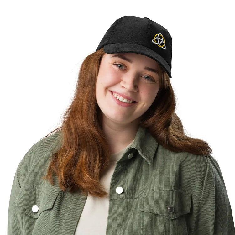 A young woman wearing a black Xigfireon vintage corduroy cap embroidered with a White & Gold Celtic Trinity Knot, offset to the left.