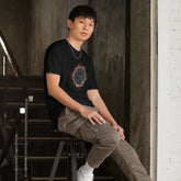 A young man wearing a classic black Xigfireon graphic tee featuring the Eclipsed iteration of the `Morning Star Fire` Celtic knot design, inspired by the Annular Solar Eclipse of 2023.