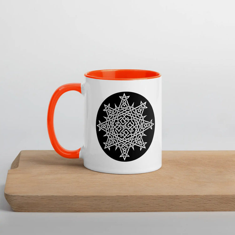 A Xigfireon white ceramic 11oz mug featuring the Black & White Circle iteration of the `Morning Star Fire` Celtic knot design, with orange handle and inside. This Celtic knot symbolizes Father Sun.