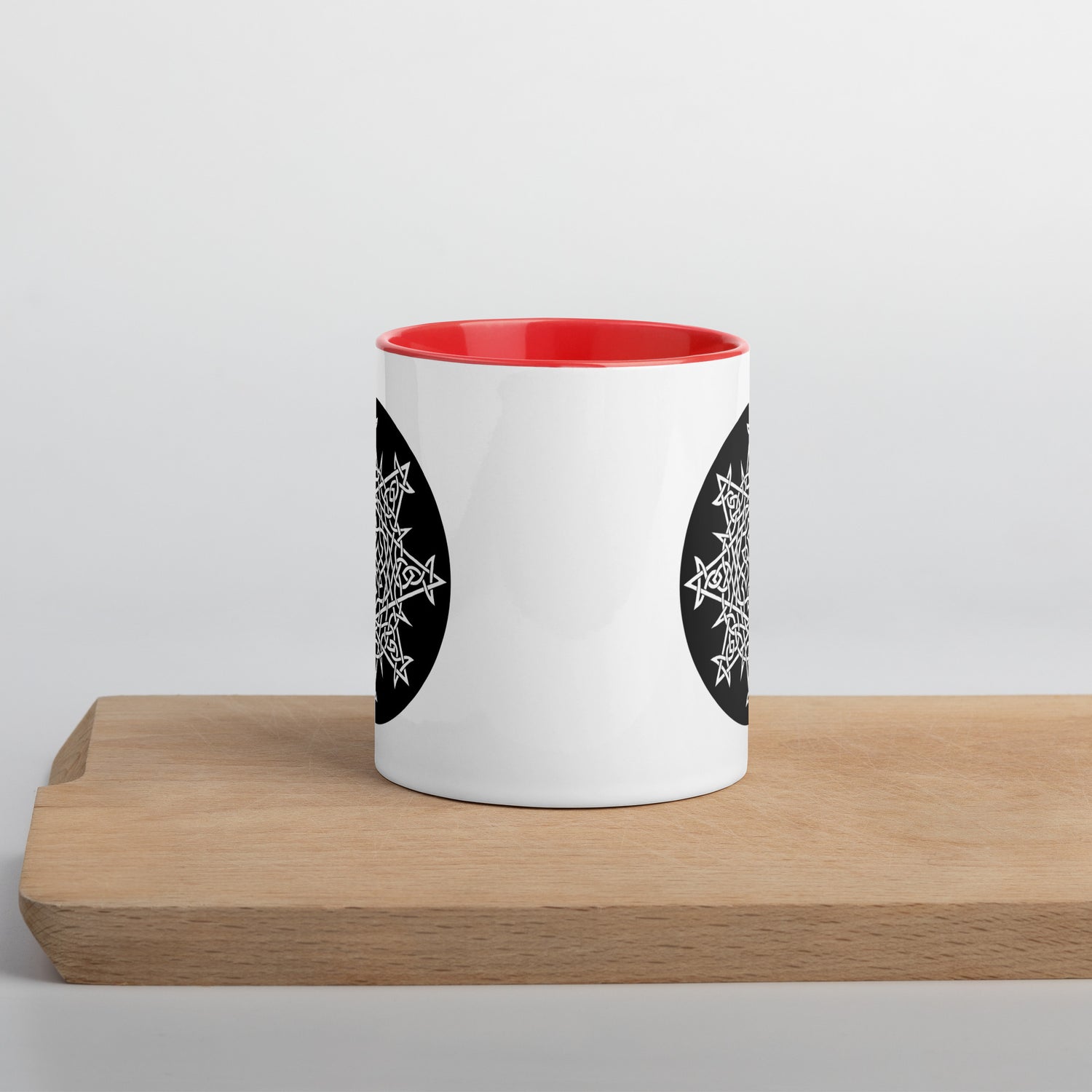 A Xigfireon white ceramic 11oz mug featuring the Black & White Circle iteration of the `Morning Star Fire` Celtic knot design, with red handle and inside. This Celtic knot symbolizes Father Sun.