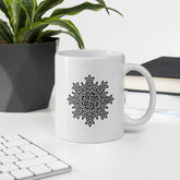 A desktop displaying a Xigfireon white glossy 11oz mug featuring the Black & White Solid iteration of the `Morning Star Fire` Celtic knot design. This Celtic knot symbolizes Father Sun.