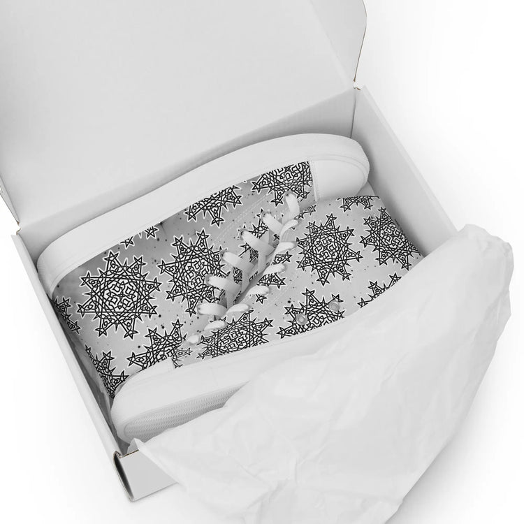 A shoebox containing a pair of canvas high tops featuring the Inverted Black & White Solid Cosmos iteration of the `Morning Star Fire` Celtic knot pattern.