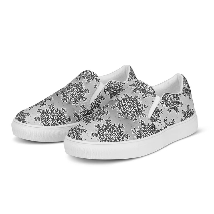 A pair of Xigfireon canvas slip-ons featuring the Inverted Black & White Solid Cosmos iteration of the `Morning Star Fire` Celtic knot pattern.