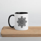 A cutting board displaying a Xigfireon white ceramic 11oz mug featuring the Black & White Solid iteration of the `Morning Star Fire` Celtic knot design, with black handle and inside. This Celtic knot symbolizes Father Sun.