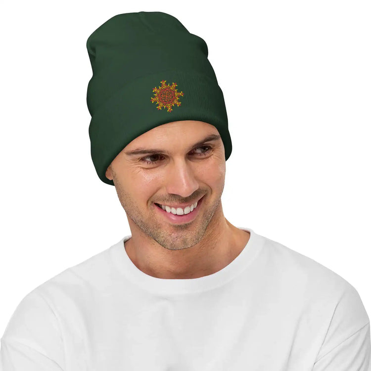 A young man wearing a dark green Xigfireon knit beanie embroidered with the Fire Colour iteration of the `Morning Star Fire` Celtic knot design.