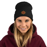 A young woman wearing a black Xigfireon knit beanie embroidered with the Fire Colour iteration of the `Morning Star Fire` Celtic knot design.