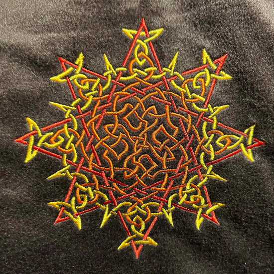 A close-up of a fireside brown Xigfireon sherpa blanket embroidered with the Fire Colour iteration of the `Morning Star Fire` Celtic knot design. The `Morning Star Fire` Celtic knot represents Father Sun.