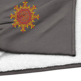 A close-up view of a heather grey Xigfireon sherpa blanket embroidered with the Fire Colour iteration of the `Morning Star Fire` Celtic knot design.