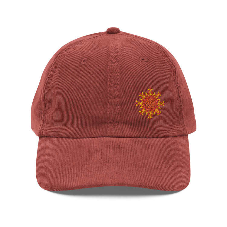 The front side of a burgundy Xigfireon vintage corduroy cap embroidered with the Fire Colour iteration of the `Morning Star Fire` Celtic knot design offset to the left.