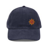 The front side of a navy blue Xigfireon vintage corduroy cap embroidered with the Fire Colour iteration of the `Morning Star Fire` Celtic knot design offset to the left.