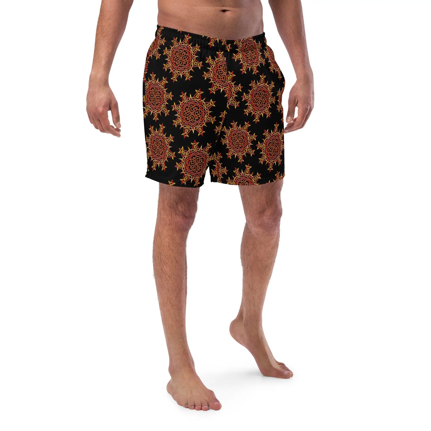 A young man wearing a pair of Xigfireon graphic swim trunks featuring the Fire Colour Black (small) patterned series of the `Morning Star Fire` Celtic knot design.