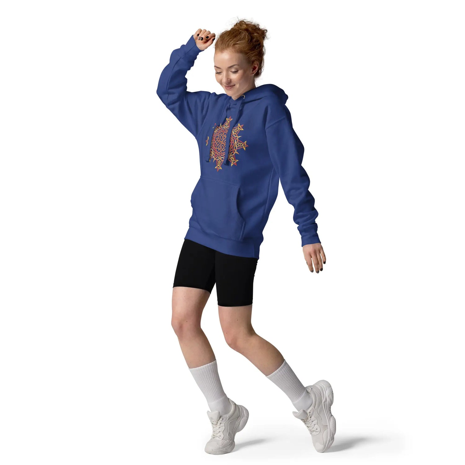 A young woman wearing a royal blue Xigfireon graphic hoodie featuring the Fire Colour iteration of the `Morning Star Fire` Celtic knot design. This Celtic knot symbolizes the Sun.