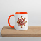 A cutting board displaying a Xigfireon white ceramic 11oz mug featuring the Fire Colour iteration of the `Morning Star Fire` Celtic knot design, with orange handle and inside. This Celtic knot symbolizes Father Sun.
