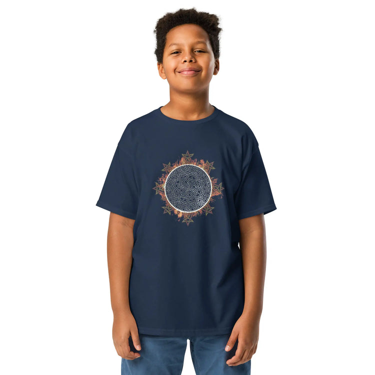 A young boy wearing a navy blue Xigfireon kids graphic t-shirt featuring the Eclipsed iteration of the `Morning Star Fire` Celtic knot design. The `Morning Star Fire` Celtic knot represents the sun.