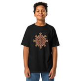 A young boy wearing a black Xigfireon kids graphic t-shirt featuring the Fire Colour iteration of the `Morning Star Fire` Celtic knot design. The `Morning Star Fire` Celtic knot represents the Sun.