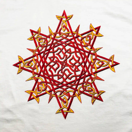 A close-up view of a white Xigfireon graphic t-shirt featuring a screen printed version of the Fire Colour iteration of the `Morning Star Fire` Celtic knot design.