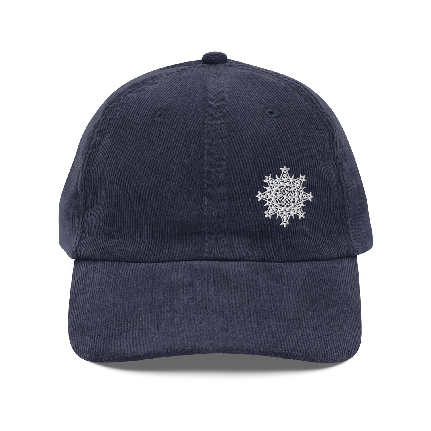 The front side of a navy blue Xigfireon vintage corduroy cap embroidered with the White iteration of the `Morning Star Fire` Celtic knot design offset to the left.