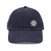 The front side of a navy blue Xigfireon vintage corduroy cap embroidered with the White iteration of the `Morning Star Fire` Celtic knot design offset to the left.