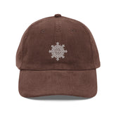 The front side of a brown Xigfireon vintage corduroy cap embroidered with the White iteration of the `Morning Star Fire` Celtic knot design.