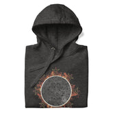 A folded charcoal heather Xigfireon graphic hoodie featuring the Eclipsed iteration of the `Morning Star Fire` Celtic knot design, inspired by the 2023 Annular Solar Eclipse.