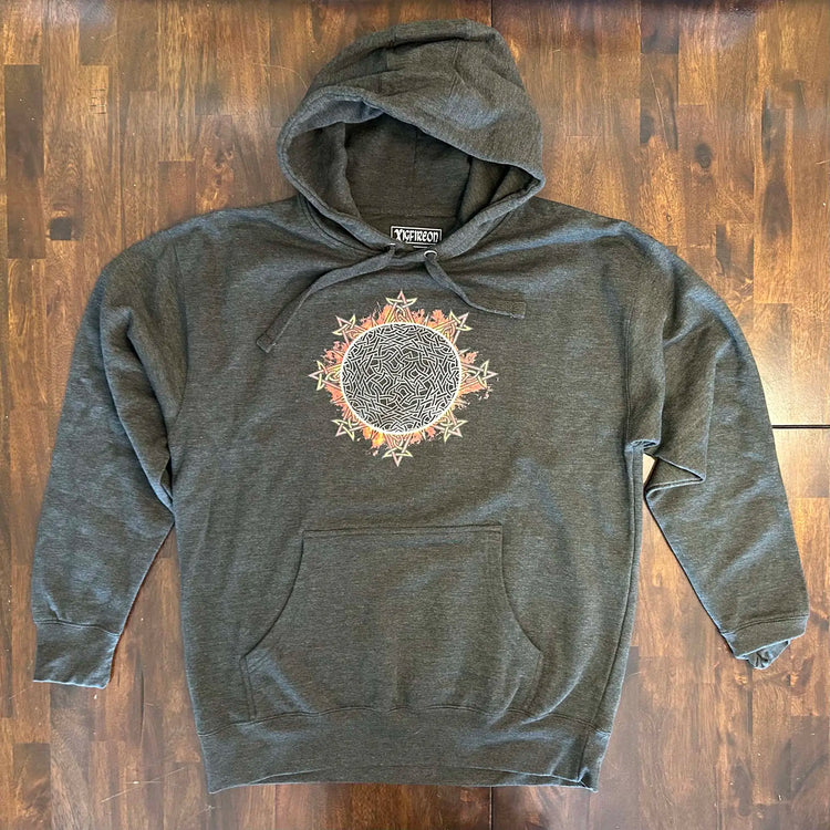 A wooden tabletop with a charcoal heather Xigfireon graphic hoodie featuring the Eclipsed iteration of the `Morning Star Fire` Celtic knot design, inspired by the 2023 Annular Solar Eclipse.