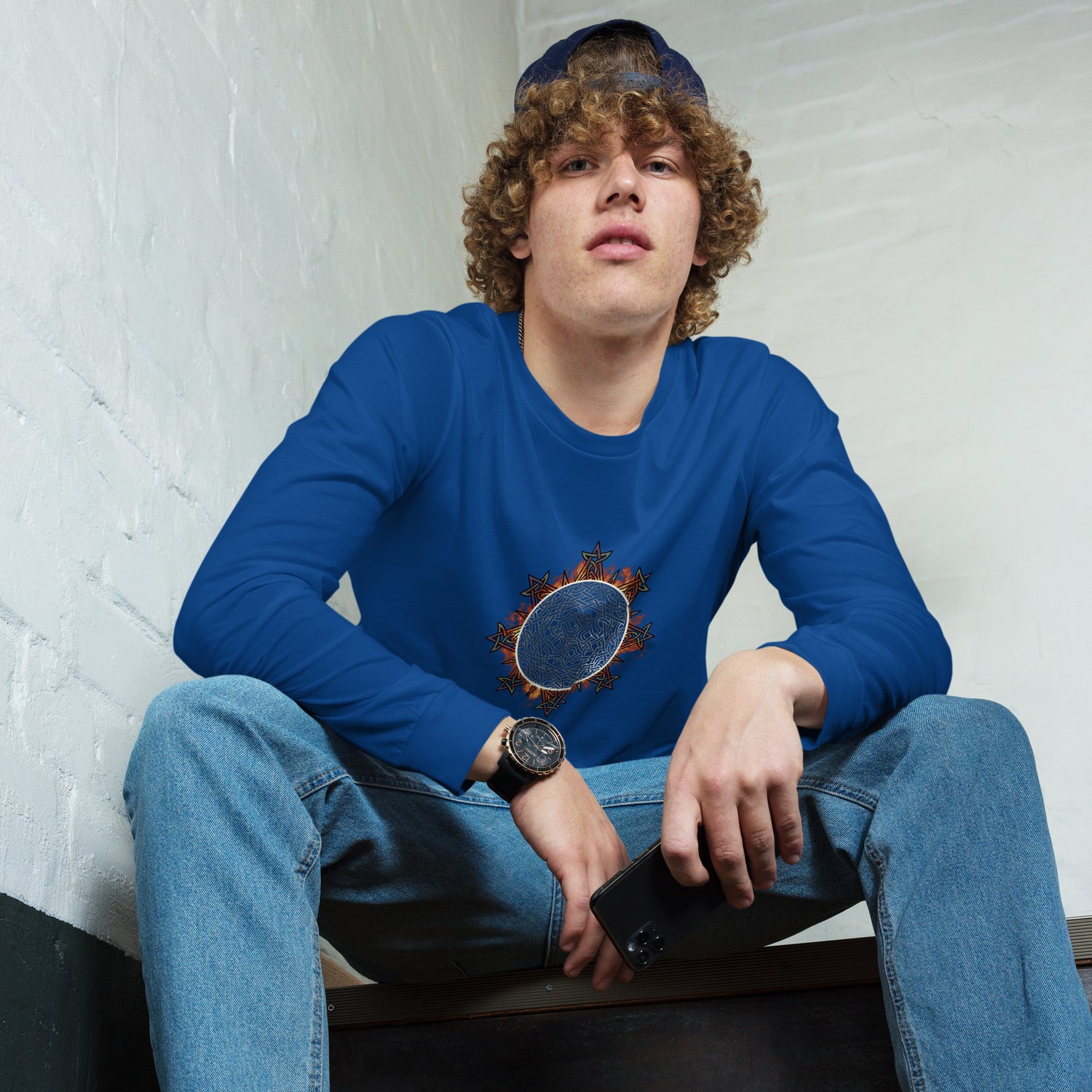 A young man wearing a true royal blue Xigfireon long sleeve graphic tee featuring the Eclipsed iteration of the `Morning Star Fire` Celtic knot design, inspired by the 2023 Annular Solar Eclipse.