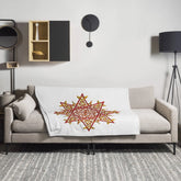 A sofa covered by a 50 inch by 60 inch Xigfireon throw blanket featuring the Fire Colour iteration of the `Morning Star Fire` Celtic knot design. The `Morning Star Fire` Celtic knot represents the Sun.