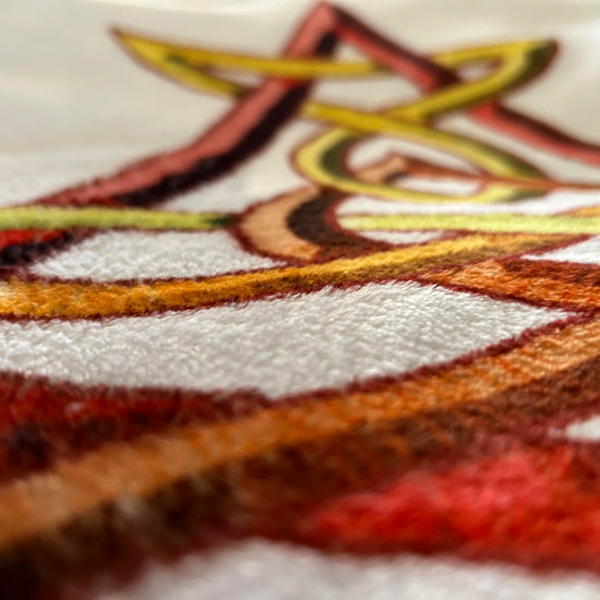 A super close-up photograph of the Xigfireon throw blanket featuring the original blazing Fire Colour iteration of the `Morning Star Fire` Celtic knot design. The `Morning Star Fire` Celtic knot represents the Sun.