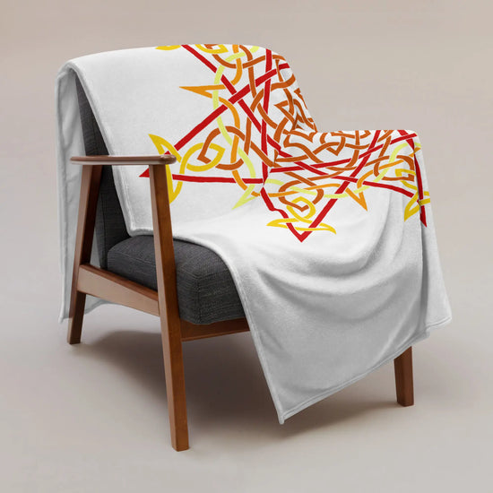 A chair covered by a 60 inch by 80 inch Xigfireon throw blanket featuring the Fire Colour Flat iteration of the `Morning Star Fire` Celtic knot design. The `Morning Star Fire` Celtic knot represents the Sun.